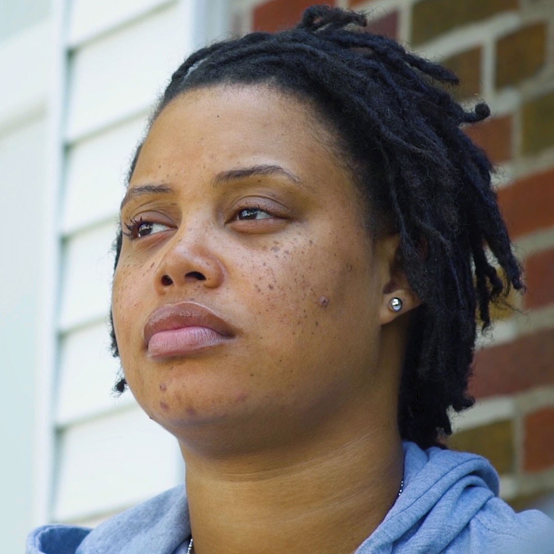 Close up of Tyana Simmons standing in front of a brick wall.