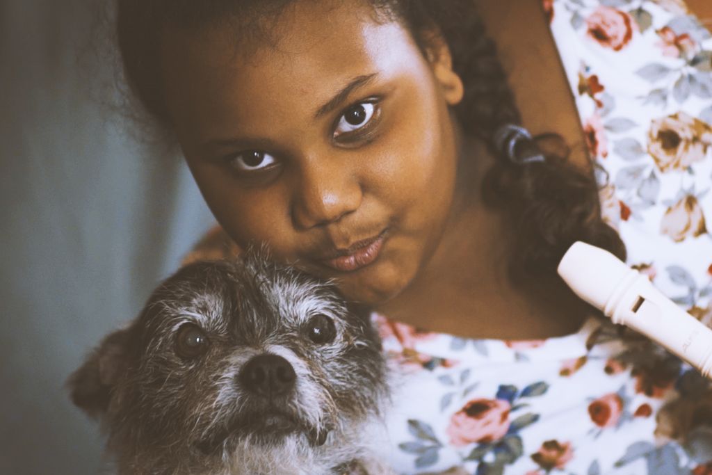 Young woman posing in a floral shirt with a terrier-mix dog.